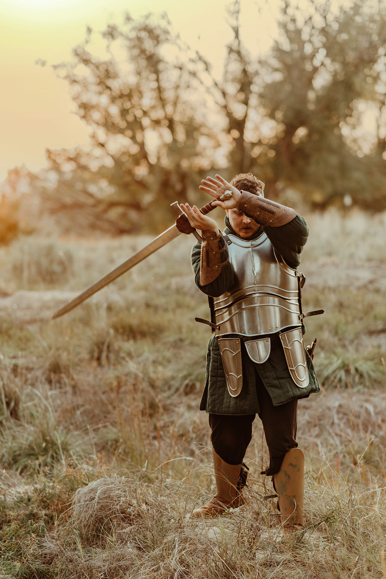 A photo of a man dressed as a knight holding a broad sword at golden hour taken by Kendra Colleen Photography, a man dressed in fantasy cosplay for family photos in Denver Colorado