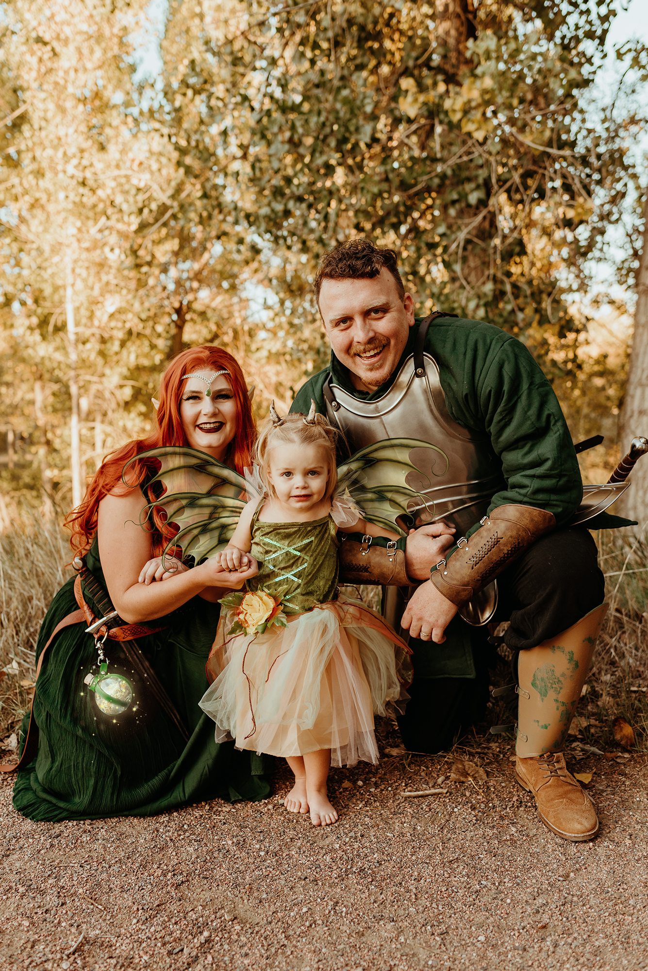 A family dressed in fantasy cosplay for family photos in Denver Colorado. A woman in an elven warrior costume, a man in a knight's costume and a little girl dressed as a fairy goblin pose for a family photo in Denver Colorado.