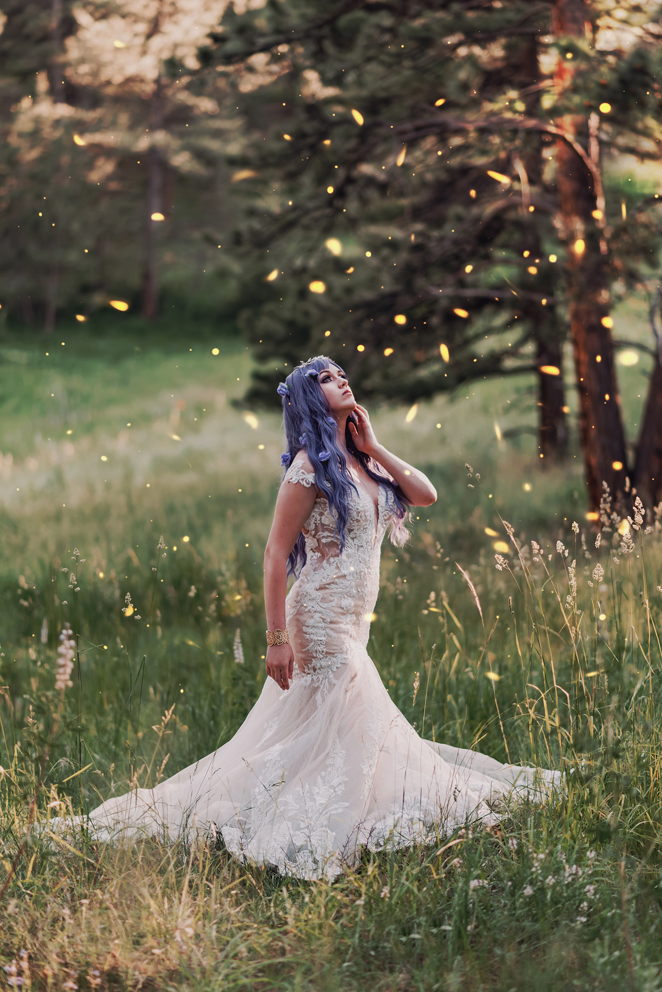A woman with purple hair, wearing a white wedding dress, stands in a field in a forest in Boulder Colorado for a fantasy bridal portrait by Kendra Colleen Photography