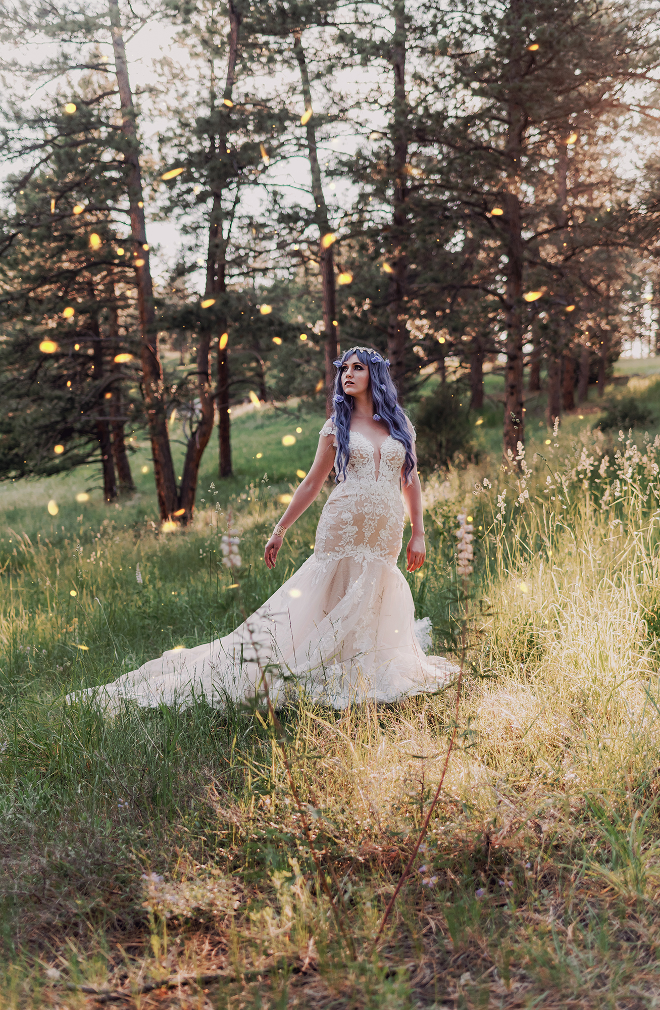 Kendra Colleen Photography takes fantasy bridal portrait of a woman with purple hair, wearing a wedding dress standing in a field in a woodland area of Boulder Colorado.