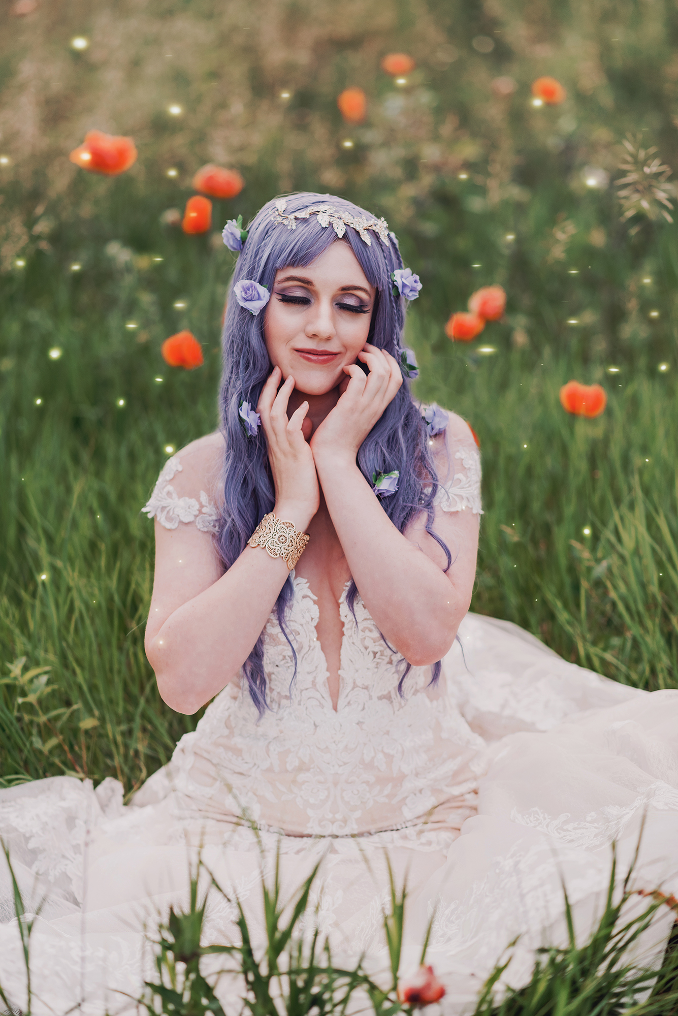 Kendra Colleen Photography takes fantasy image of a woman with purple hair sitting in a field of grass and wildflowers, she wears a white dress and a gold bracelet.