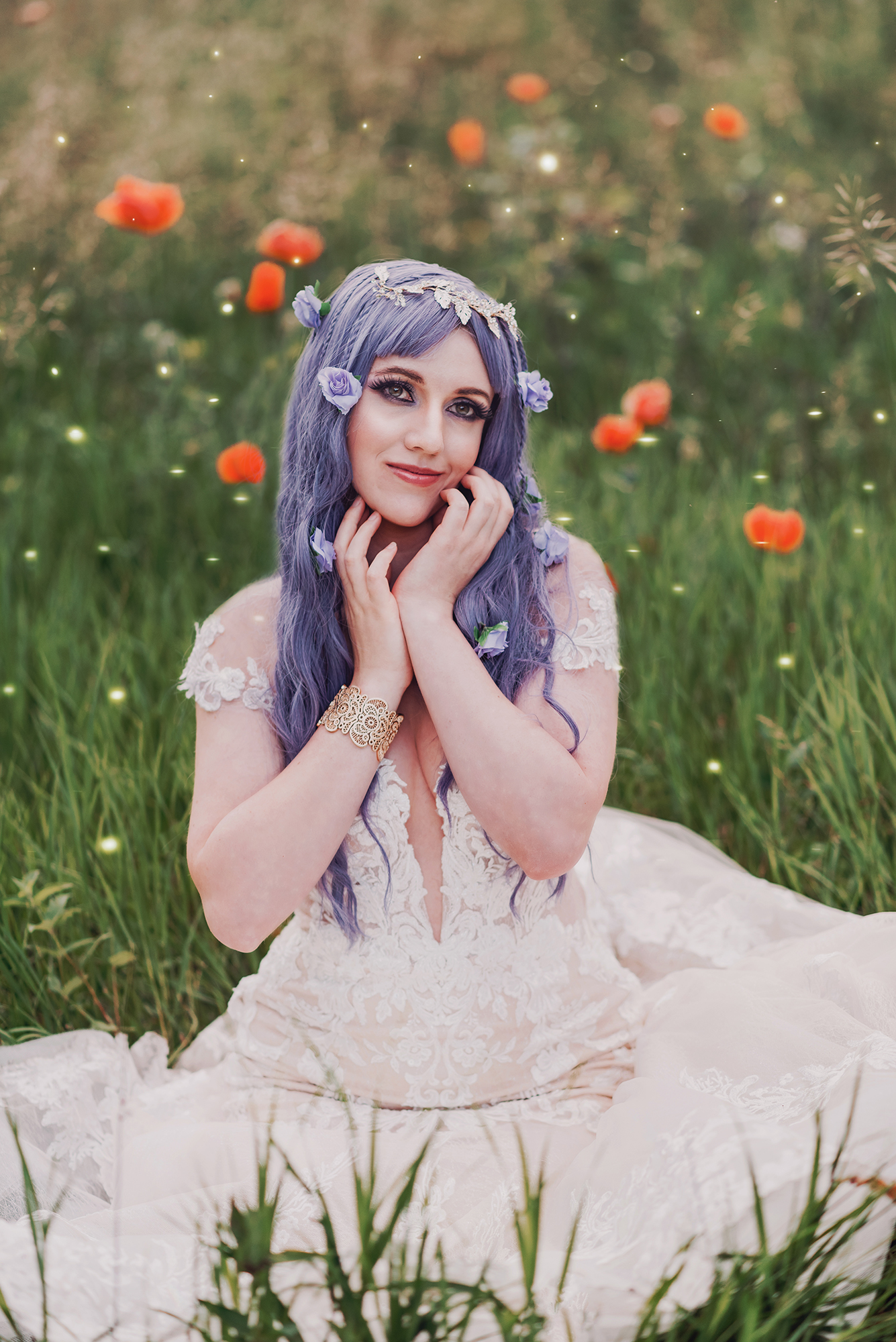 Fantasy portrait taken by Kendra Colleen Photography of a woman with purple hair sitting in a field of green grass and flowers wearing a white dress.