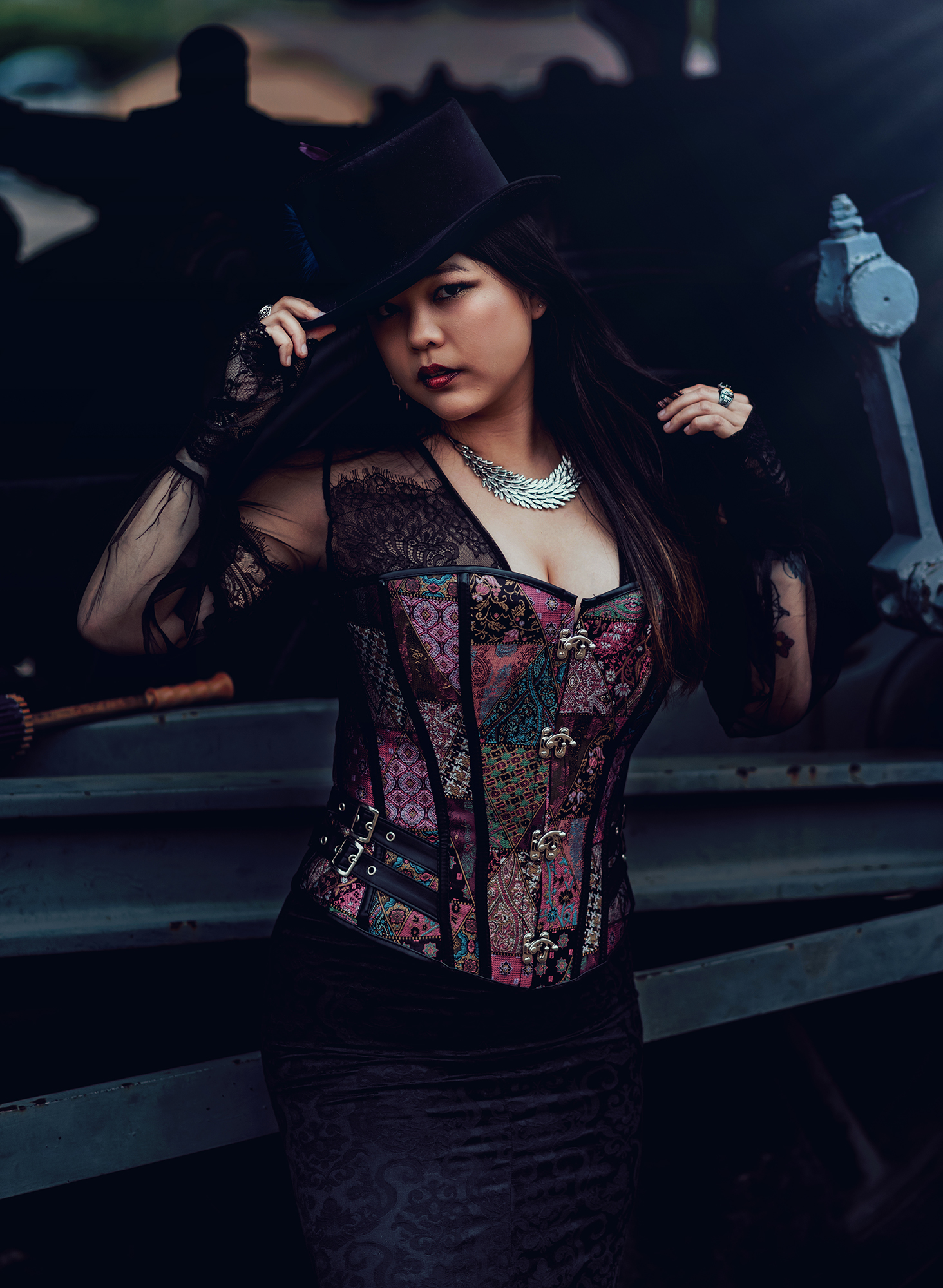 A woman wearing a top hat and colorful corset for a steampunk style photo by Kendra Colleen Photography in Denver Colorado