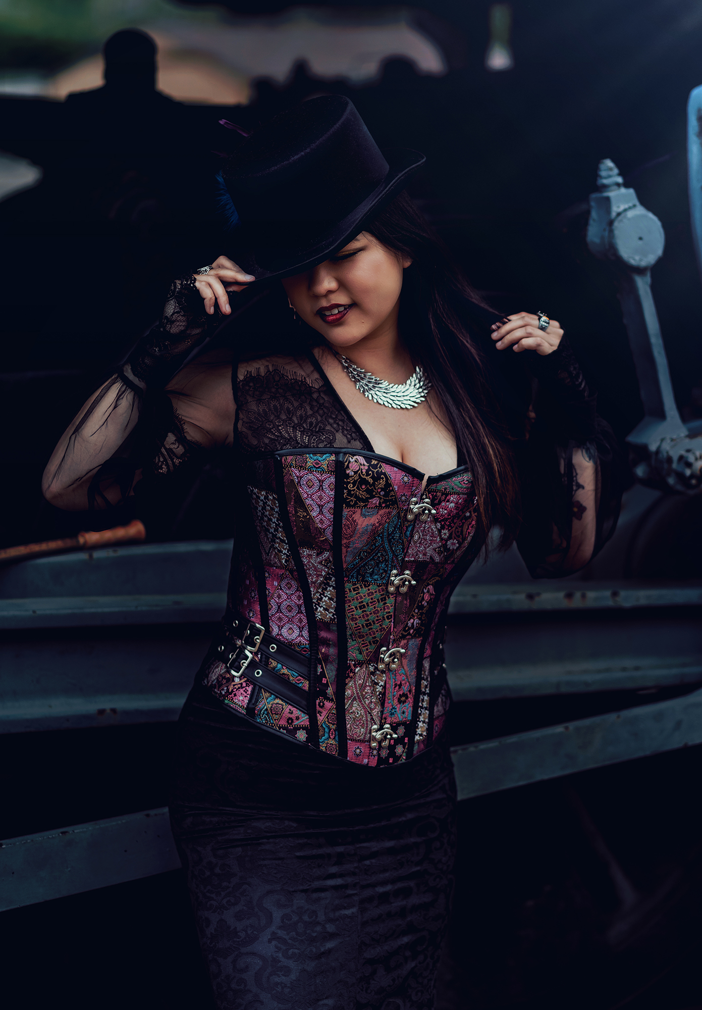 A woman wearing a colorful corset and a top hat for steampunk style fantasy photo.
