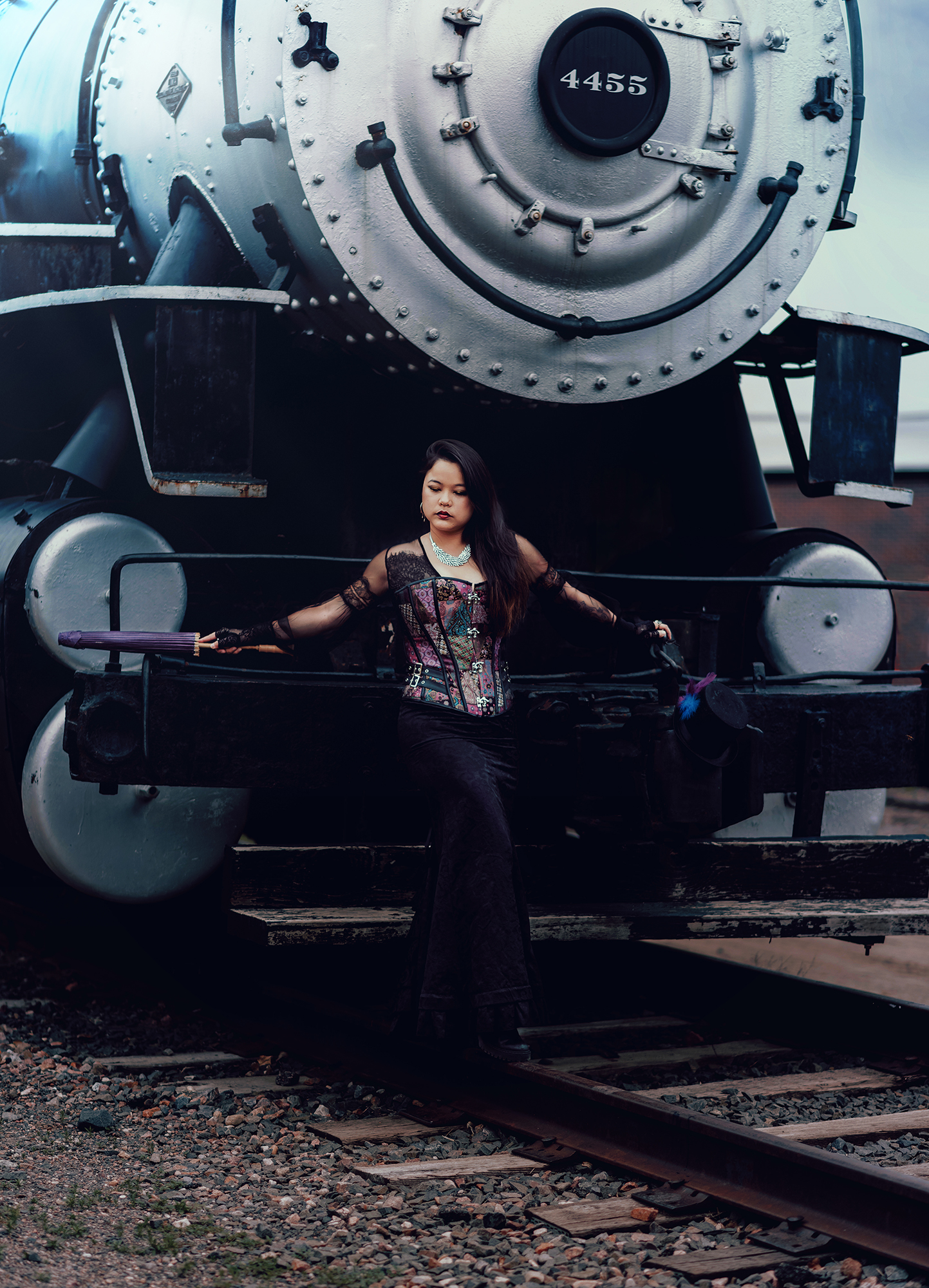 Woman standing in front of a vintage steam engine train wearing a Victorian style steampunk outfit for a fantasy photo by Kendra Colleen Photography in Denver Colorado